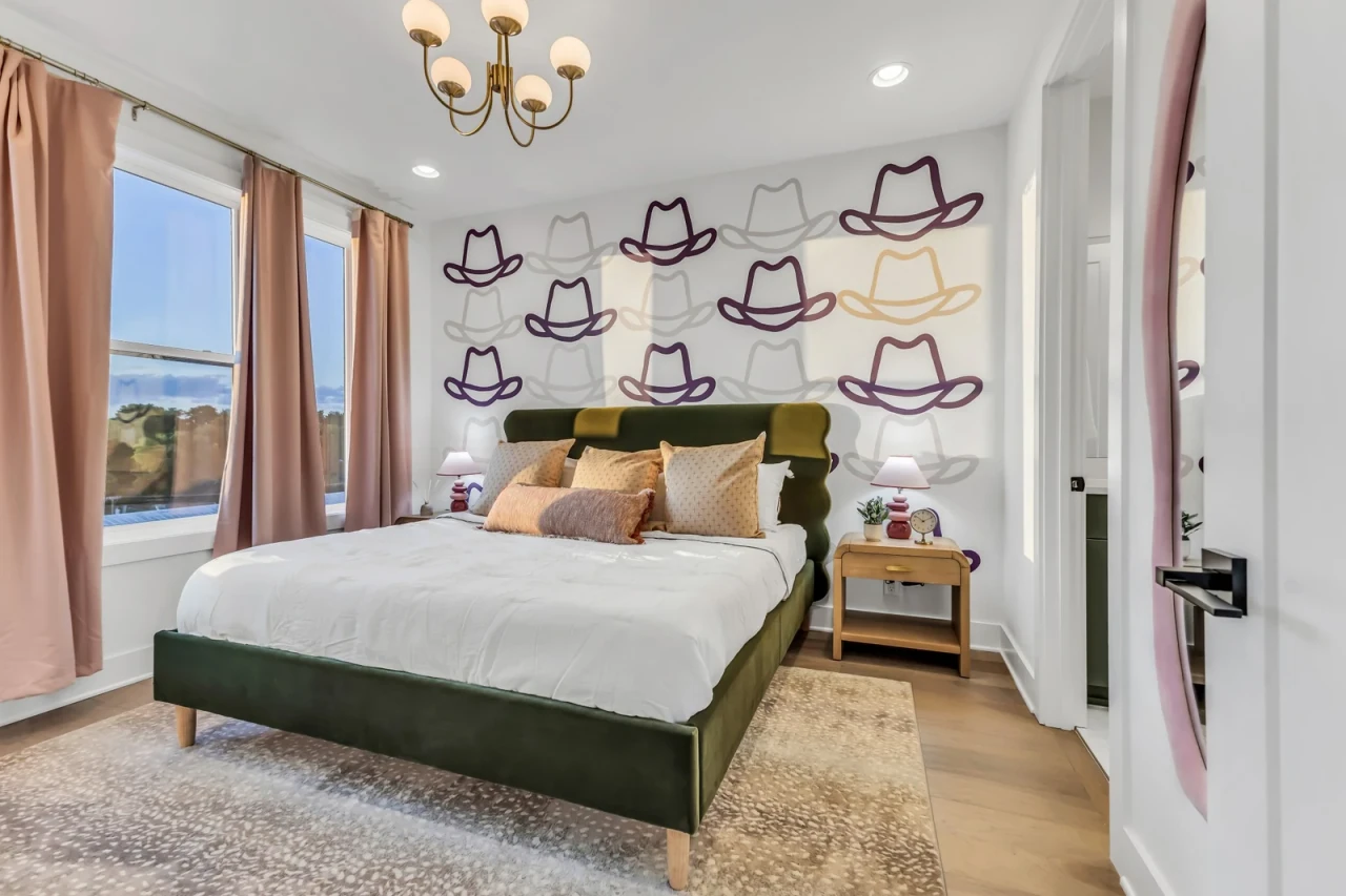 Nashville rental bedroom with cowboy-hat wallpaper and a green velvet bed
